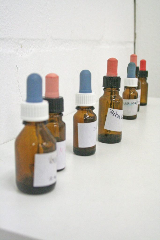Seven pipette bottles lined up on a white shelf in a white room